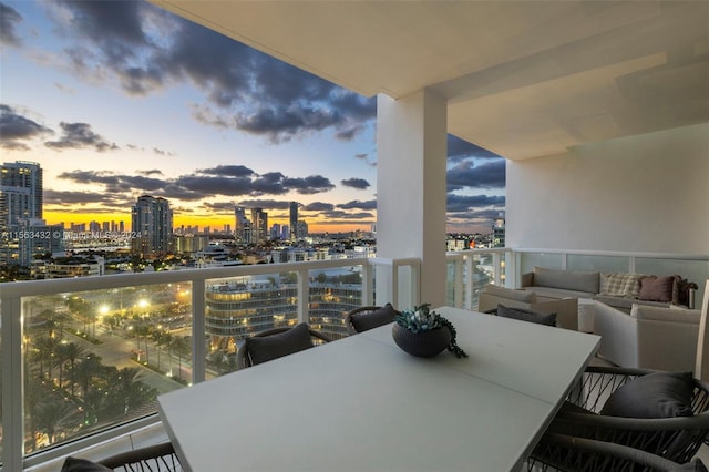 balcony at dusk featuring a view of city, outdoor dining area, and outdoor lounge area