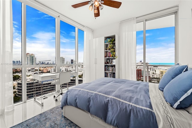 bedroom with a view of city, floor to ceiling windows, a water view, a ceiling fan, and access to outside