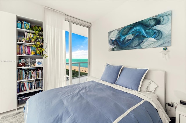 bedroom with access to exterior, floor to ceiling windows, and a water view