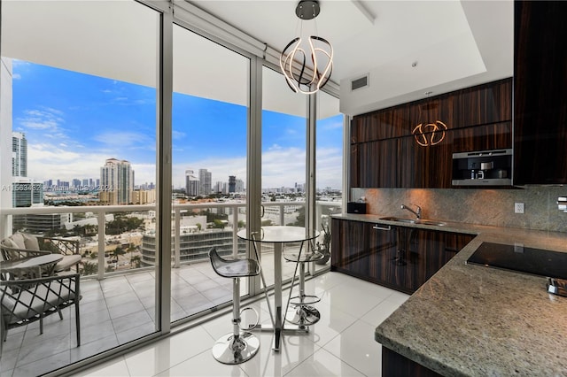 kitchen with a sink, decorative backsplash, a view of city, a wall of windows, and modern cabinets