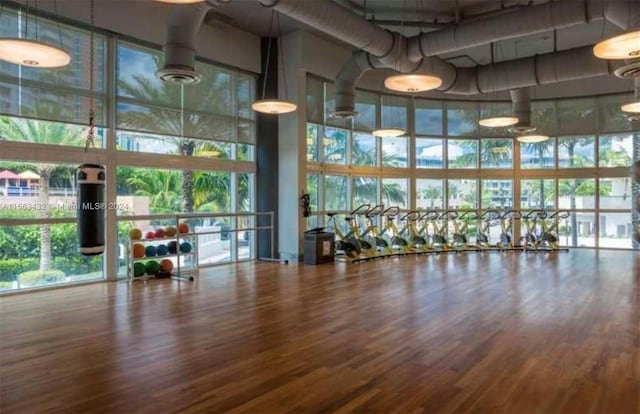 interior space with a towering ceiling, floor to ceiling windows, and wood finished floors