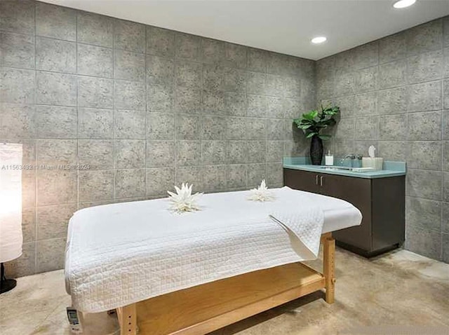 bedroom with a sink, tile walls, concrete flooring, and recessed lighting