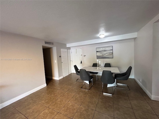 dining room featuring dark tile floors and a textured ceiling