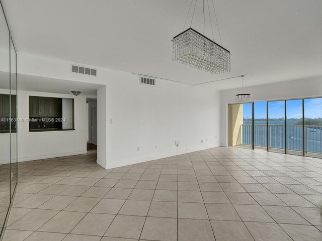 empty room with light tile flooring and a water view