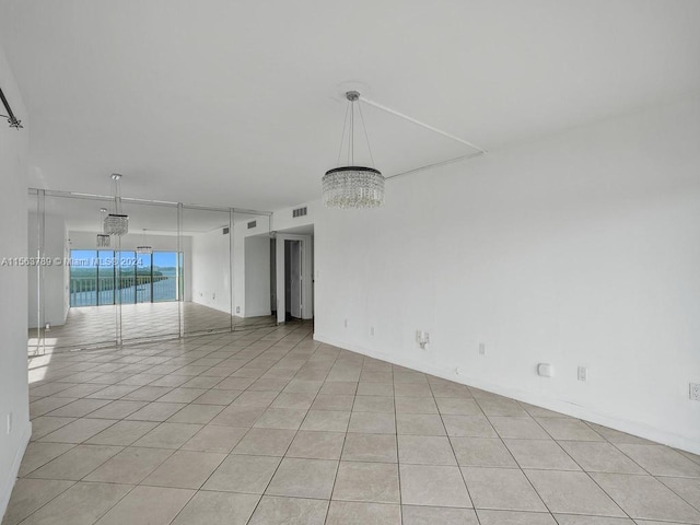 empty room featuring light tile floors and a notable chandelier