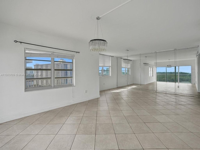 spare room with light tile floors and a notable chandelier