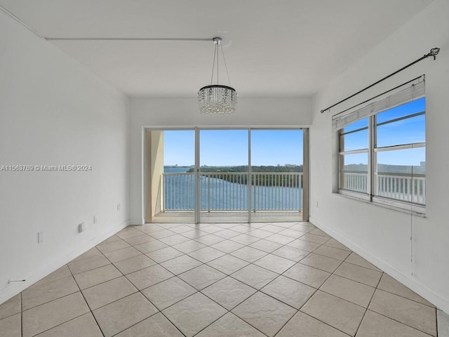 spare room featuring a healthy amount of sunlight, a water view, and light tile flooring