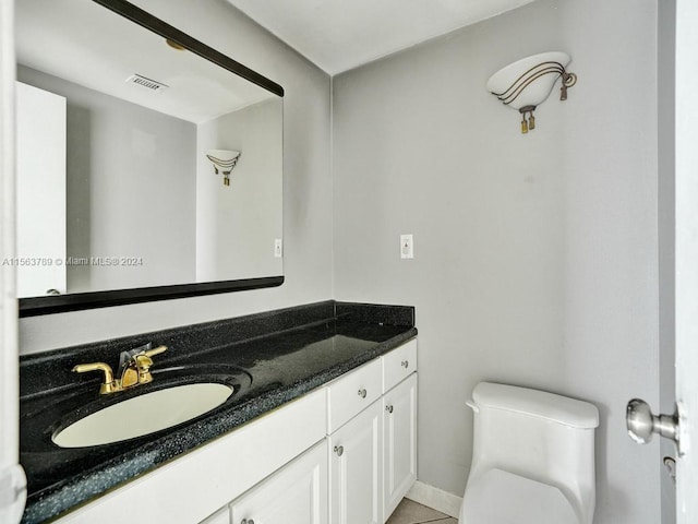 bathroom featuring tile floors, vanity, and toilet