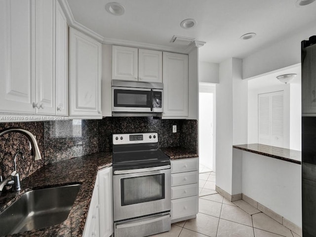 kitchen featuring white cabinets, light tile flooring, stainless steel appliances, sink, and tasteful backsplash