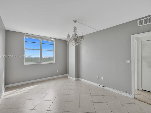 tiled spare room with a chandelier