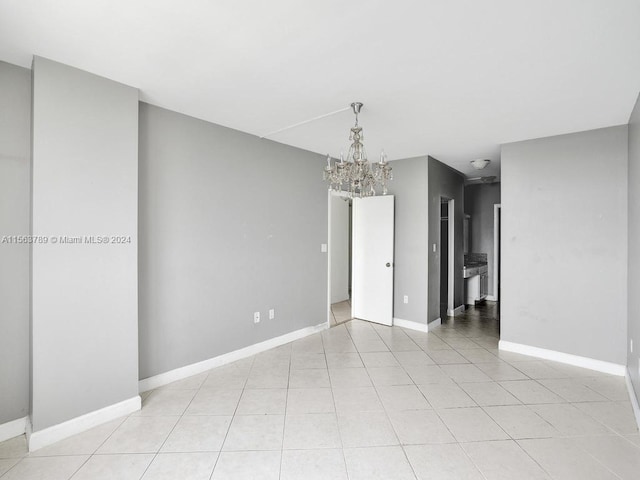 tiled empty room featuring an inviting chandelier