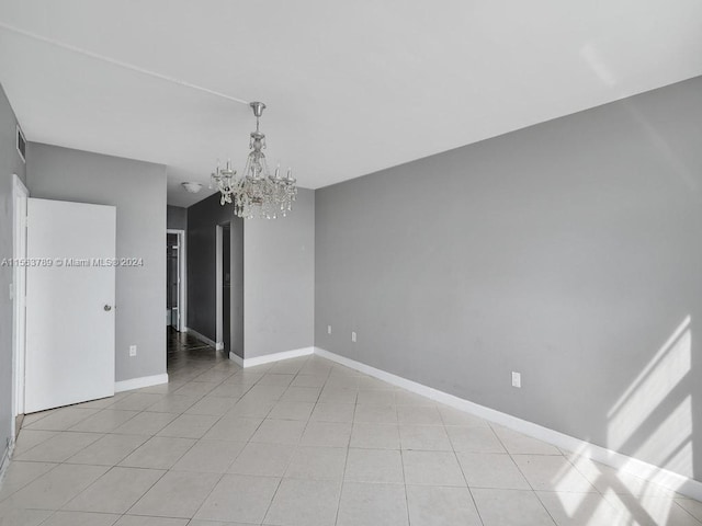 empty room featuring a chandelier and light tile flooring