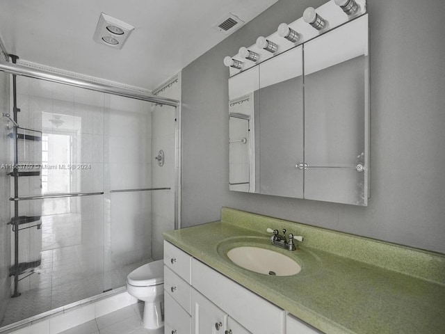 bathroom featuring tile flooring, a shower with door, vanity with extensive cabinet space, and toilet