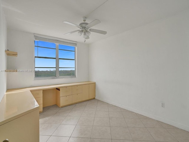 tiled spare room with built in desk and ceiling fan