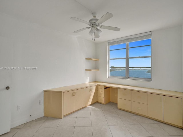 unfurnished office with ceiling fan, light tile floors, and a water view