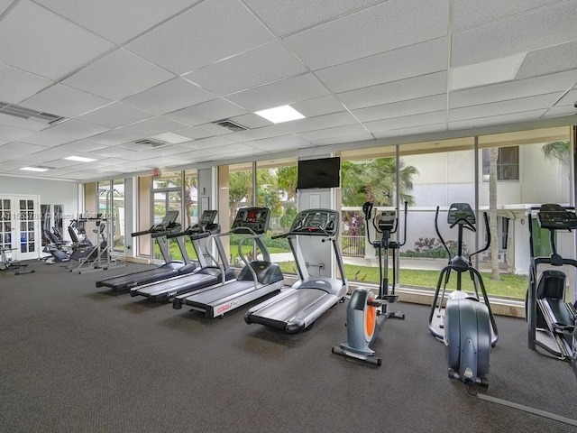 exercise room featuring a drop ceiling, french doors, and dark colored carpet