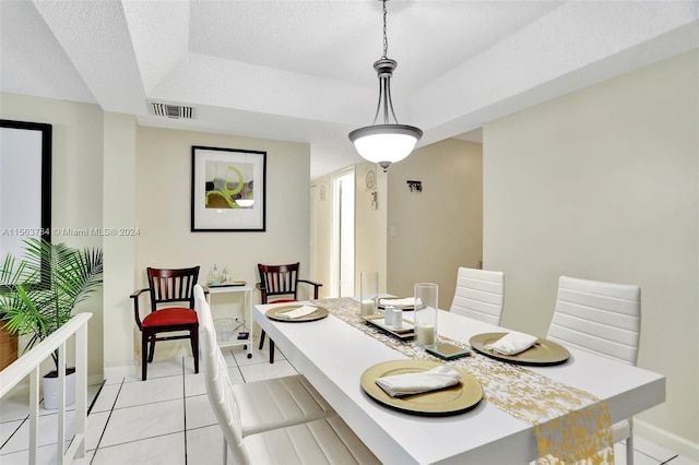 tiled dining room featuring a raised ceiling and a textured ceiling