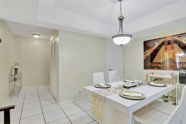 dining space with light tile patterned floors and a raised ceiling