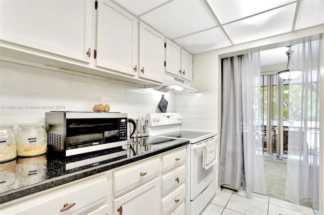 kitchen with white electric stove, white cabinets, a drop ceiling, dark stone counters, and light tile patterned floors