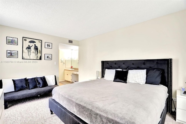 carpeted bedroom with connected bathroom and a textured ceiling