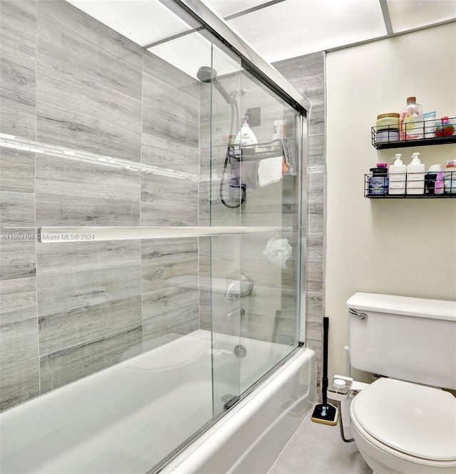 bathroom with bath / shower combo with glass door and toilet