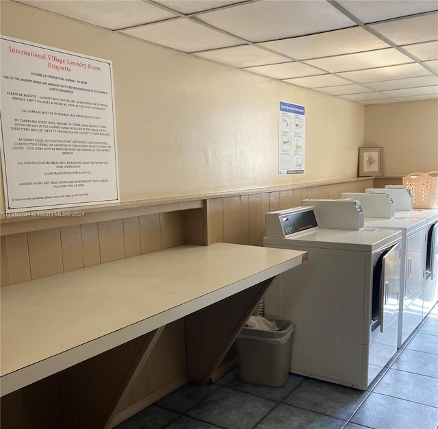 clothes washing area featuring wood walls, independent washer and dryer, and tile patterned floors