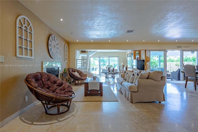 tiled living room featuring a healthy amount of sunlight and a textured ceiling