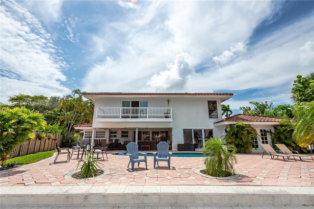 back of property with a patio, a balcony, and a fenced in pool