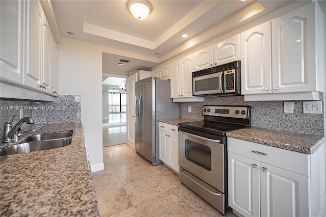 kitchen with backsplash, stainless steel appliances, a raised ceiling, and white cabinetry