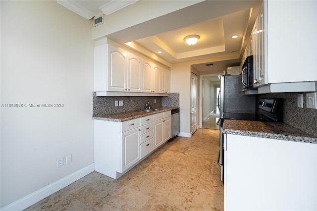 kitchen with stainless steel appliances, dark stone counters, tasteful backsplash, white cabinets, and a raised ceiling