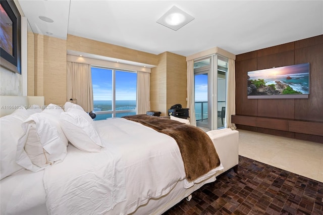 bedroom featuring a water view, dark tile floors, and access to exterior