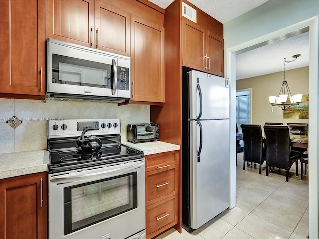 kitchen with stainless steel appliances, backsplash, decorative light fixtures, light tile patterned floors, and a chandelier