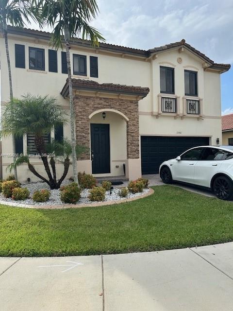 mediterranean / spanish home with a front lawn and a garage