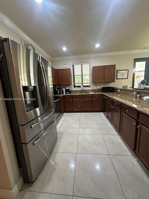 kitchen with light stone counters, ornamental molding, stainless steel refrigerator with ice dispenser, and light tile floors