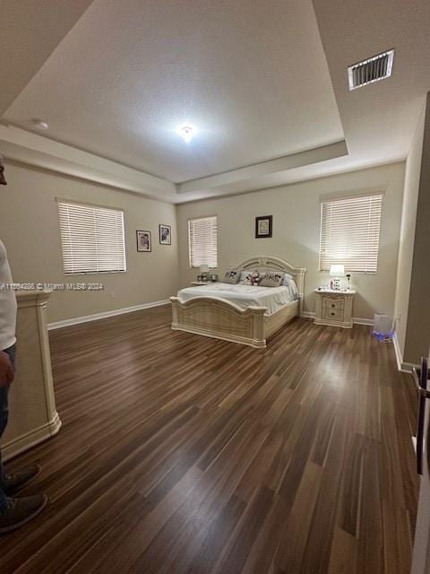 unfurnished bedroom with dark hardwood / wood-style floors and a tray ceiling