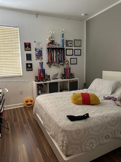 bedroom with crown molding and dark wood-type flooring