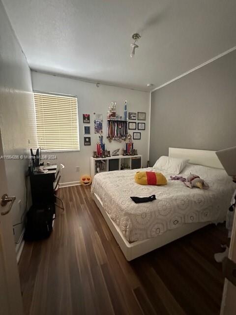 bedroom with crown molding and dark wood-type flooring