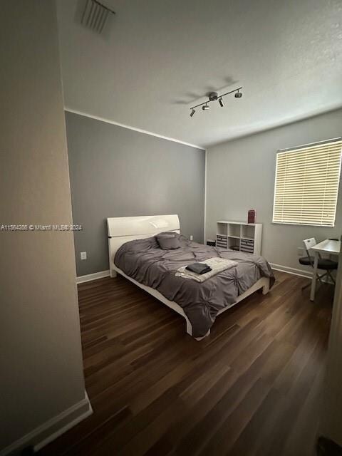 bedroom with dark wood-type flooring and rail lighting