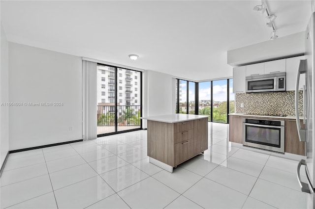 kitchen with a kitchen island, white cabinetry, stainless steel appliances, decorative backsplash, and floor to ceiling windows