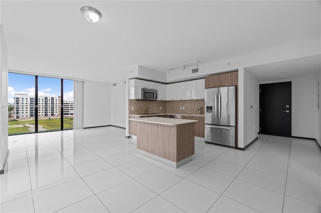 kitchen featuring floor to ceiling windows, a center island, decorative backsplash, stainless steel appliances, and white cabinets