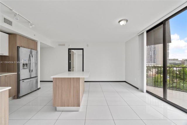 kitchen with stainless steel refrigerator with ice dispenser, a kitchen island, floor to ceiling windows, and plenty of natural light