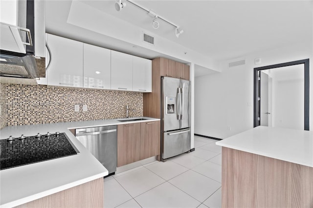 kitchen with white cabinetry, stainless steel appliances, decorative backsplash, sink, and light tile patterned flooring