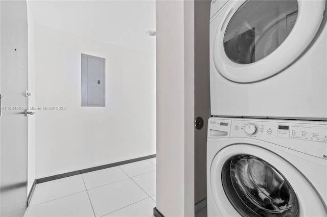 laundry area with light tile patterned floors, electric panel, and stacked washer and clothes dryer