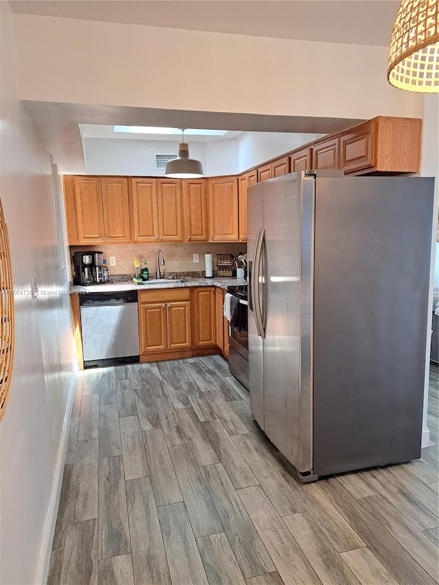 kitchen featuring light hardwood / wood-style flooring, sink, stainless steel appliances, and backsplash