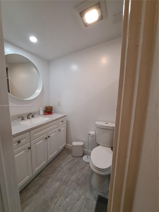 bathroom with toilet, vanity, and tile flooring