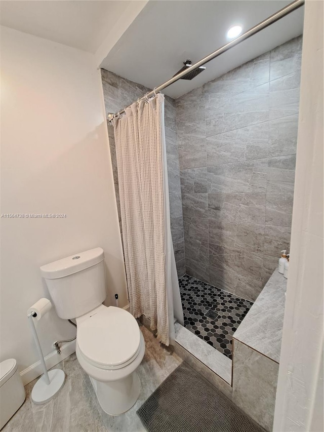 bathroom with curtained shower, tile flooring, and toilet