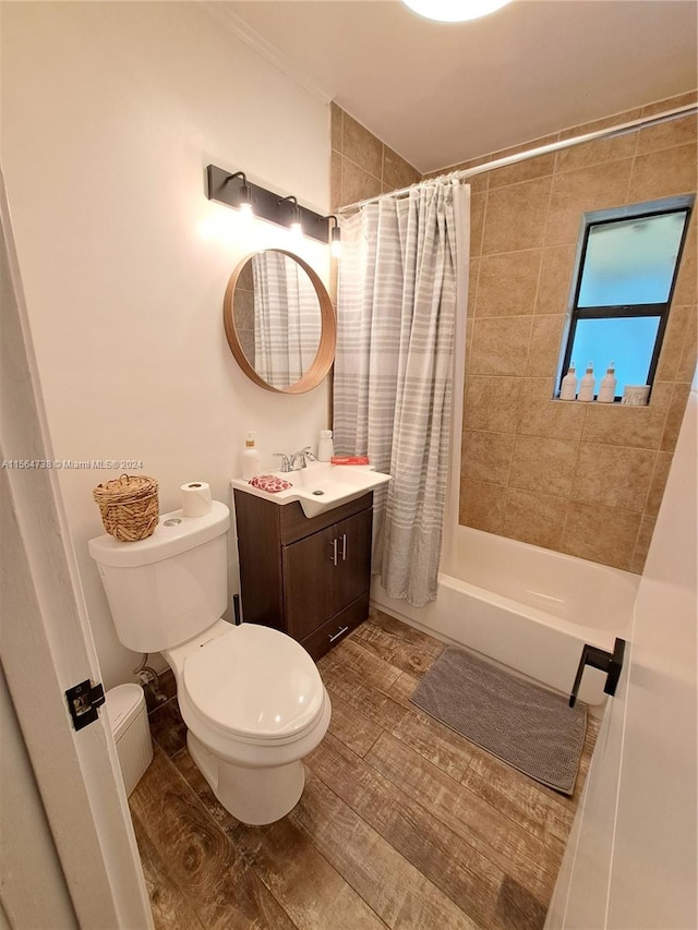 full bathroom featuring hardwood / wood-style flooring, vanity, shower / bath combo with shower curtain, and toilet