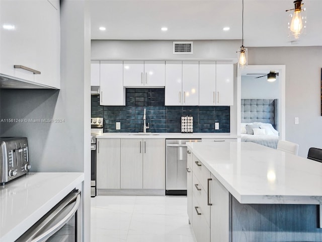 kitchen with sink, light tile floors, dishwasher, decorative light fixtures, and white cabinetry