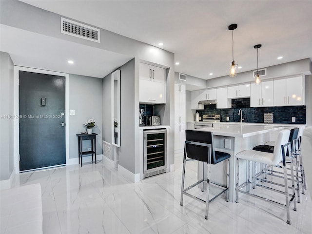 kitchen featuring white cabinets, a breakfast bar area, wine cooler, electric stove, and pendant lighting