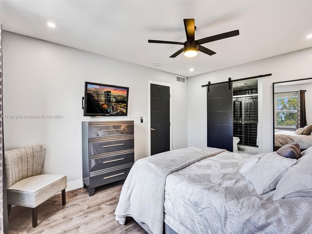 bedroom featuring a barn door, ceiling fan, and light hardwood / wood-style flooring